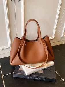 Brown lychee grain leather tote bag with dual straps on a stylish studio background