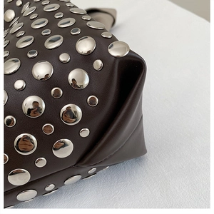 Detailed close-up of dark brown leather handbag with metallic silver stud embellishments