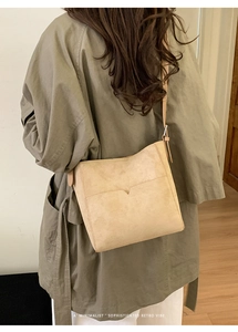 Vue détaillée du sac seau beige en daim avec coutures en V minimalistes et rétro