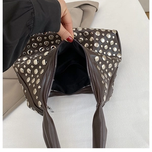 Close-up of brown studded shoulder bag interior with black lining and secure zipper pocket