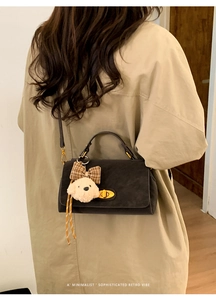 Close-up of retro crossbody bag with golden twist lock and plush puppy charm