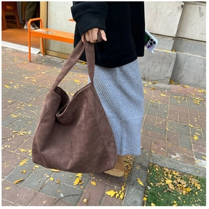 Détail d'un grand sac cabas en daim marron avec texture souple et large bandoulière de mode