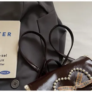 Detail of dark brown glossy leather backpack with pearl heart and bow on suit jacket
