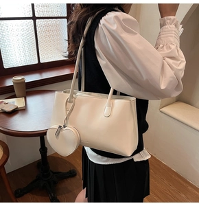 Close-up of a white glossy leather handbag with heart-shaped coin purse and embossed logo