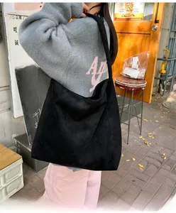 Détail de la bandoulière large d'un sac cabas en daim noir porté avec style par un mannequin