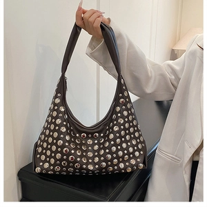 Detail of dark brown leather handbag featuring varied silver metal rivet studs