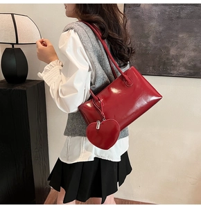 Close-up of a glossy red patent leather tote bag with a matching heart coin purse