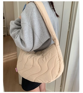 Dettaglio della borsa hobo trapuntata beige con cuciture a onda e tracolla larga