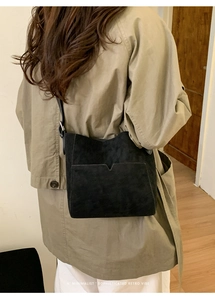 Vue arrière d'un mannequin portant le sac seau noir minimaliste en faux daim avec poche en V