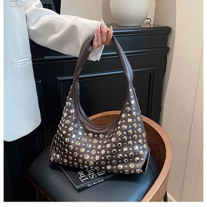 Detail of brown leather hobo bag with silver metallic studs and wide handle