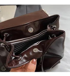 Detail of glossy brown tote bag featuring silver magnetic closure and striped lining