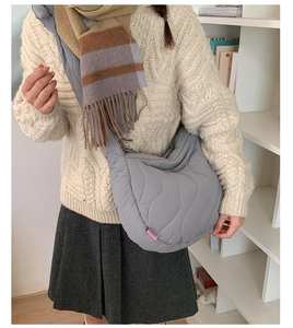 Borsa a spalla trapuntata grigia con maglione bianco a trecce e sciarpa abbinata