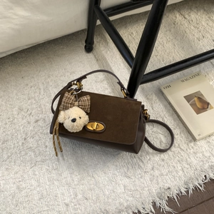 Detail of brown suede tote bag with golden metal twist lock and cute plush puppy charm