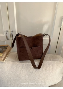 Détail du sac seau en daim marron foncé avec bandoulière en cuir et poche avant en V