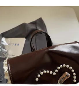 Detailed close-up of a brown leather backpack with pearls and a checkered ribbon bow