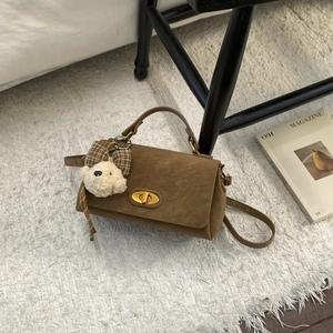 Detail of vintage suede handbag with golden twist lock and plush bear charm