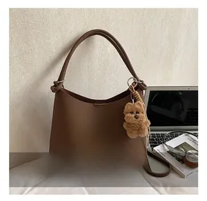 Détail du sac fourre-tout en cuir marron foncé avec charm d'ours et fermeture éclair