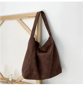 Détail du sac cabas en daim marron foncé montrant la texture mate et la large bandoulière