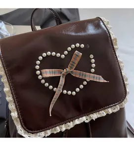Close-up of brown PU leather backpack with pearl heart, lace trim and plaid bow detail