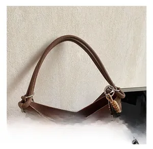 Détail du sac à main en cuir marron grainé avec poignée ronde et pendentif chien en peluche