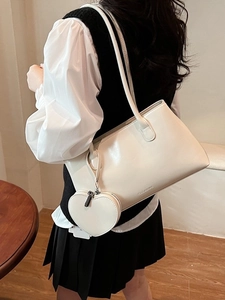 Chic cream white leather tote bag with heart charm shown on a stylish model