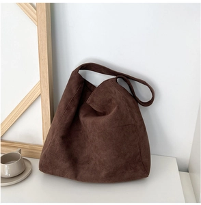Gros plan du sac cabas en daim chocolat montrant la texture mate et le design souple