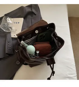 Detail view showing spacious interior of dark brown PU leather backpack with essentials