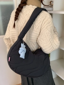Black quilted crescent crossbody bag with wave texture and a blue knot charm detail