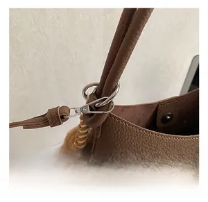 Détail macro du crochet en métal argenté et texture du cuir grainé marron du sac