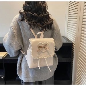 Détail d'un sac à dos style ballet-core avec bordure en dentelle et pendentif cœur perlé