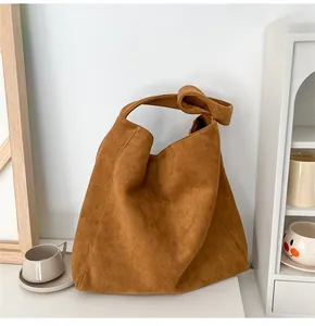 Détail du sac hobo en daim marron avec un nœud élégant sur la bandoulière pour un look chic