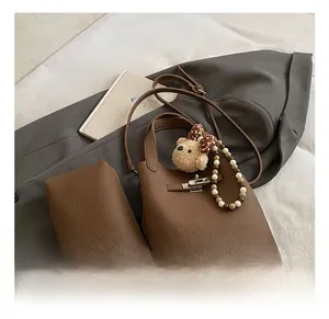 Détail du sac seau en cuir grainé marron foncé avec charm doudou et bandoulière