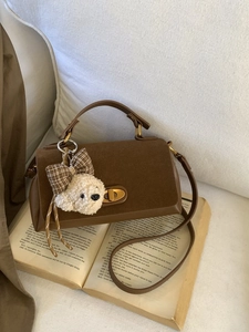 Vintage brown suede handbag with a plush puppy charm and antique bronze twist lock