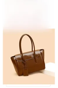 Detail of glossy brown vintage tote bag with slender handles and square leather tag