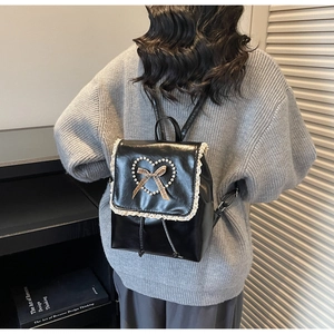 Détail d'un sac à dos en similicuir noir avec bordure dentelle et cœur en perles