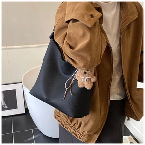Détail du sac hobo en cuir noir avec un joli pendentif d'ours en peluche marron