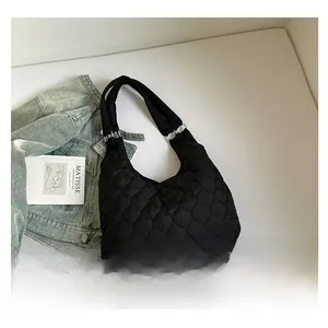 Détail du sac à bandoulière matelassé noir avec coutures nuages à côté d'un livre