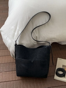 Minimalist black matte leather bucket bag with V-cut pocket and adjustable strap