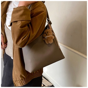 Modèle portant un grand sac cabas taupe avec un charmant petit ours en peluche brun