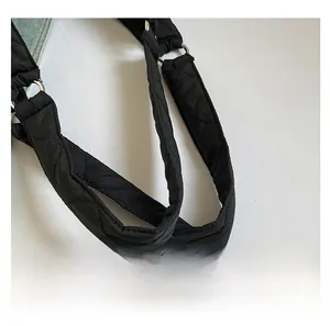 Détail de la poignée matelassée noire et de l'anneau métallique sur le sac fourre-tout