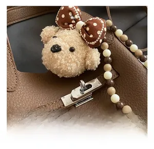 Détail du sac seau en cuir grainé marron avec fermoir argenté et charm ours en peluche