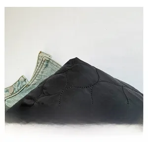 Détail du tissu matelassé noir avec coutures en losange sur un sac à bandoulière