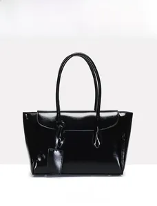 Front view of a sleek black patent leather tote bag with glossy finish and slim handles