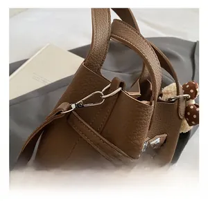 Détails du sac en cuir marron grainé avec crochet en métal argenté et breloque ours