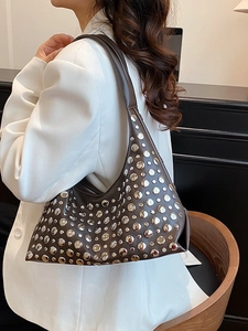 Brown leather hobo bag with silver rivets and integrated shoulder strap on model