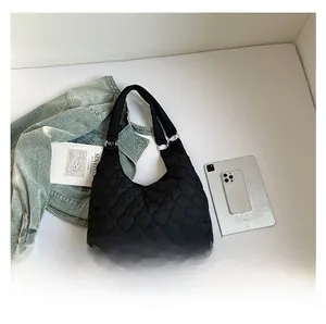 Détail du sac fourre-tout noir matelassé avec anneaux en métal argenté et motif de losanges