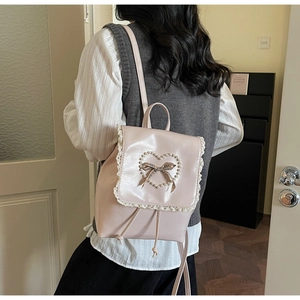 Detail eines rosa Rucksacks mit weißer Spitze, Perlenherz und karierter Schleife Dekoration