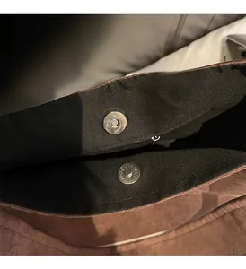 Detailed macro view of the silver magnetic snap closure and inner zipper on a brown suede bag