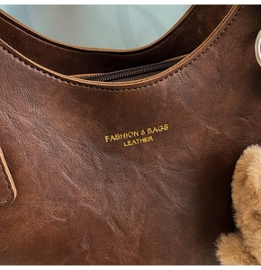 Detailed macro view of dark brown leather texture and golden printed logo on hobo bag