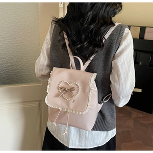 Detailansicht des rosa Rucksacks mit Perlenherz, Karoschleife und Spitzenverzierung
